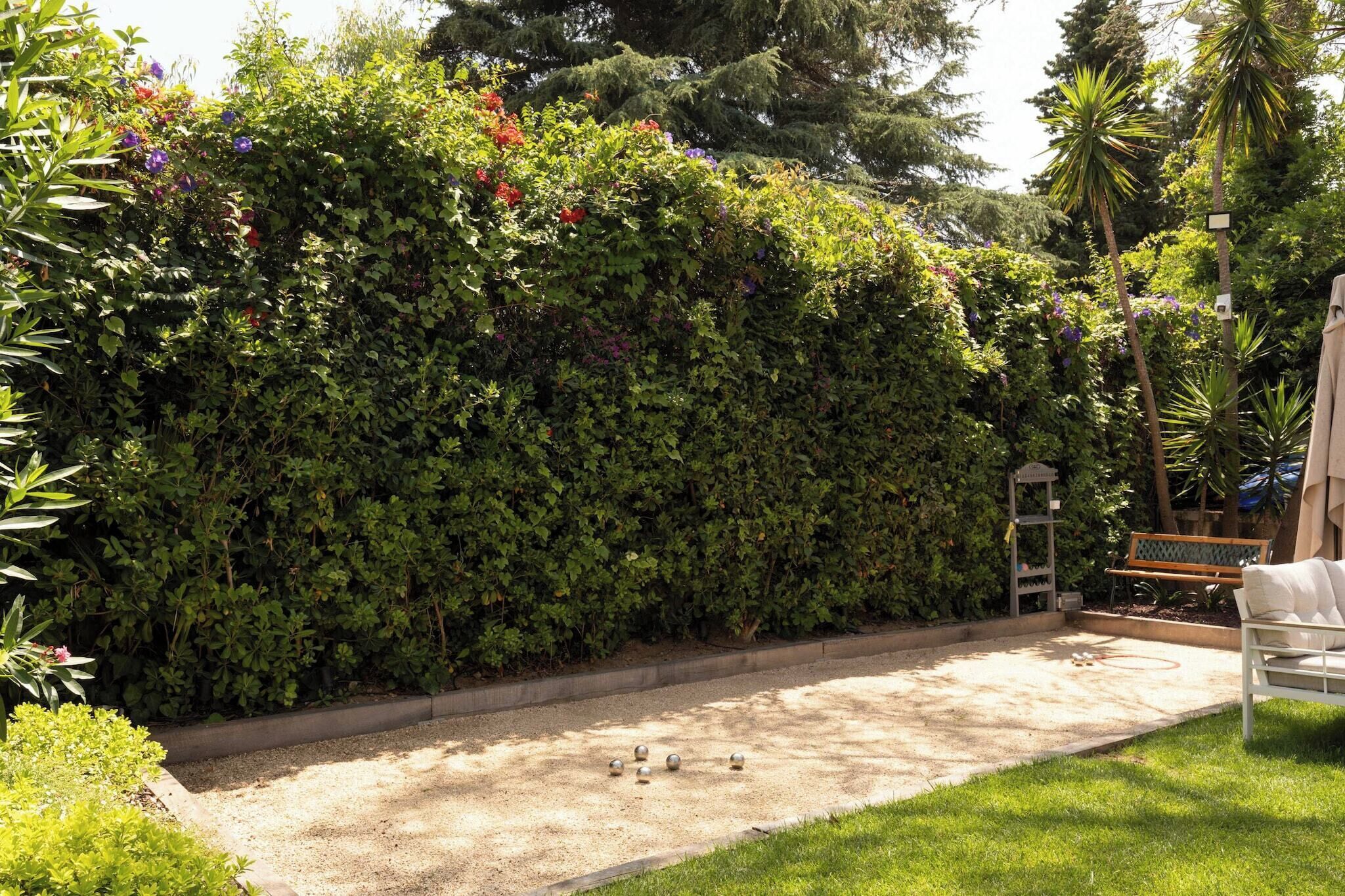Ein Garten mit Hecke, Bank und Weg.