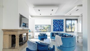 Una sala de estar moderna con chimenea de piedra, sofás azules y un ventanal con vista a la ciudad.
