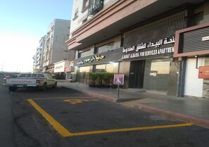 Un edificio con un cartel de apartamentos con servicios y una camioneta Toyota estacionada al frente.