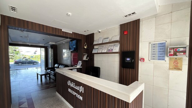 A reception area with a wooden reception desk, a seating area with chairs, and a wall-mounted information board. - AlBaidaa AlSalam branch (Madinah)