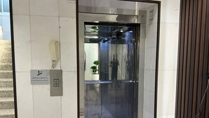 An elevator with a glass door, a fire alarm, and a small potted plant inside. - AlBaidaa AlSalam branch (Madinah)