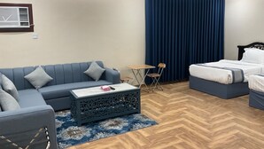 A modern room with a blue sofa, a small table, a bed, and a decorative coffee table. - AlBaidaa AlSalam branch (Madinah)