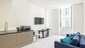 A modern kitchen with a flat-screen TV, a dining area with two chairs, and a sofa with teal cushions. - Beautiful Two bedroom apartment near Croisette (Cannes)