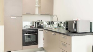 A modern kitchen with beige cabinetry, a built-in oven, a microwave, and a sink with a faucet. - Beautiful Two bedroom apartment near Croisette (Cannes)