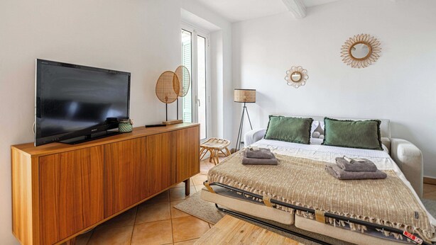 Een moderne slaapkamer met een houten tv-meubel, een bed met groene kussens en een vloerlamp.