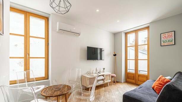A living room with a sofa, clear chairs, a small table, and a TV.