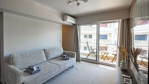 A modern living room with a sofa, a ceiling fan, and a view of the outside balcony.