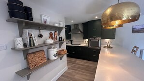A modern kitchen with dark cabinets, a white countertop, and a hanging light fixture.