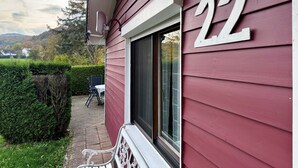 Une maison avec le numéro « 22 » sur le côté, une fenêtre et un patio avec un banc.