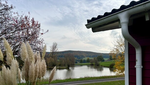 Une vue d’un lac entouré de verdure, avec un bâtiment à la façade rouge.