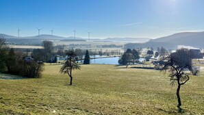 Un paysage rural avec des éoliennes, un lac et un ciel dégagé.