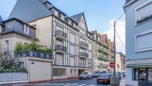 Vista de una calle con arquitectura europea tradicional, incluyendo un edificio con techo a dos aguas y un balcón.
