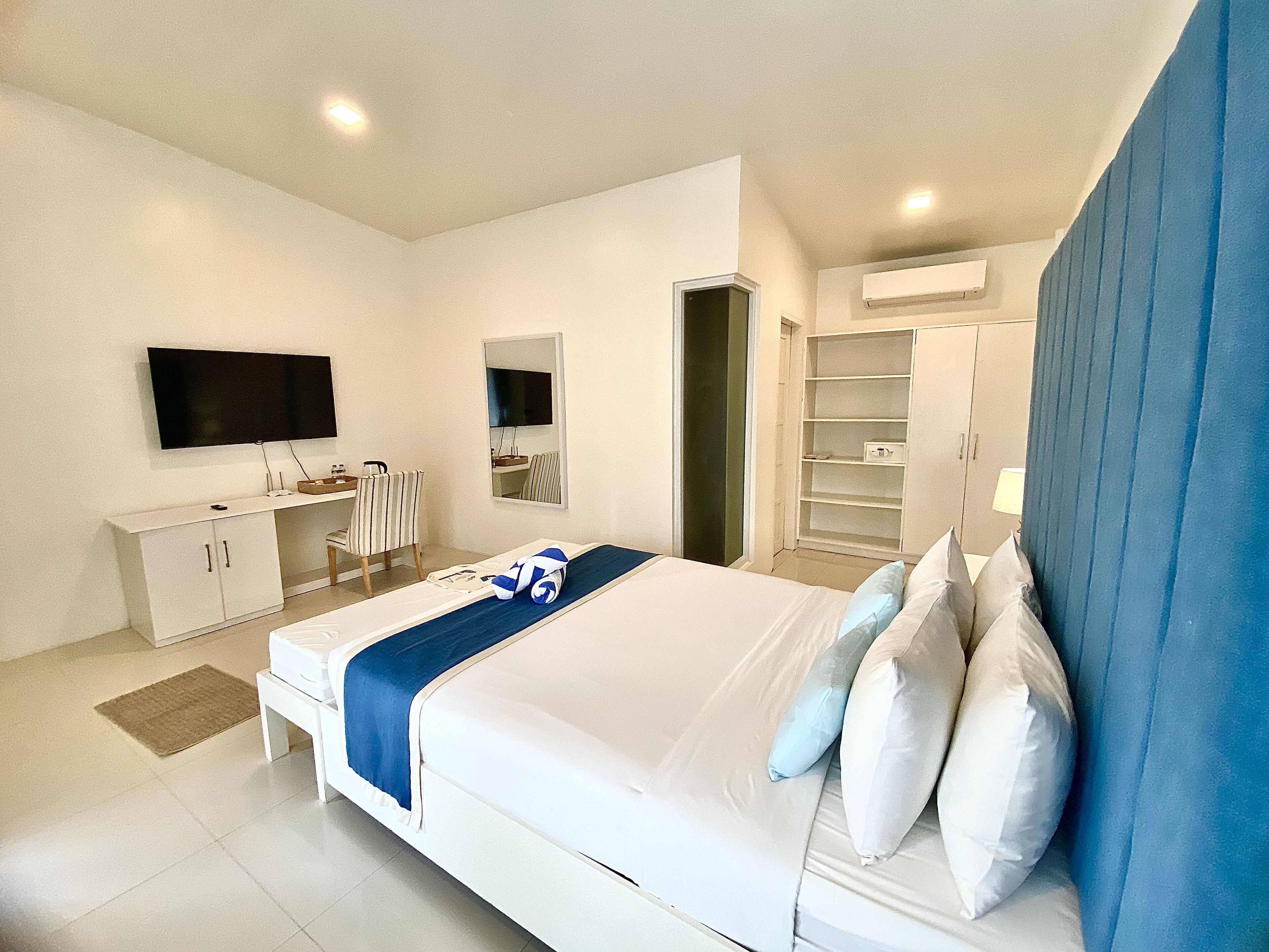 A modern bedroom with a bed, a desk, a chair, a TV, and a wardrobe.