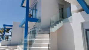 A modern staircase with glass railings leading to a second-floor landing. - Recidencia Del Hamor Beachfront (Santa Magdalena)