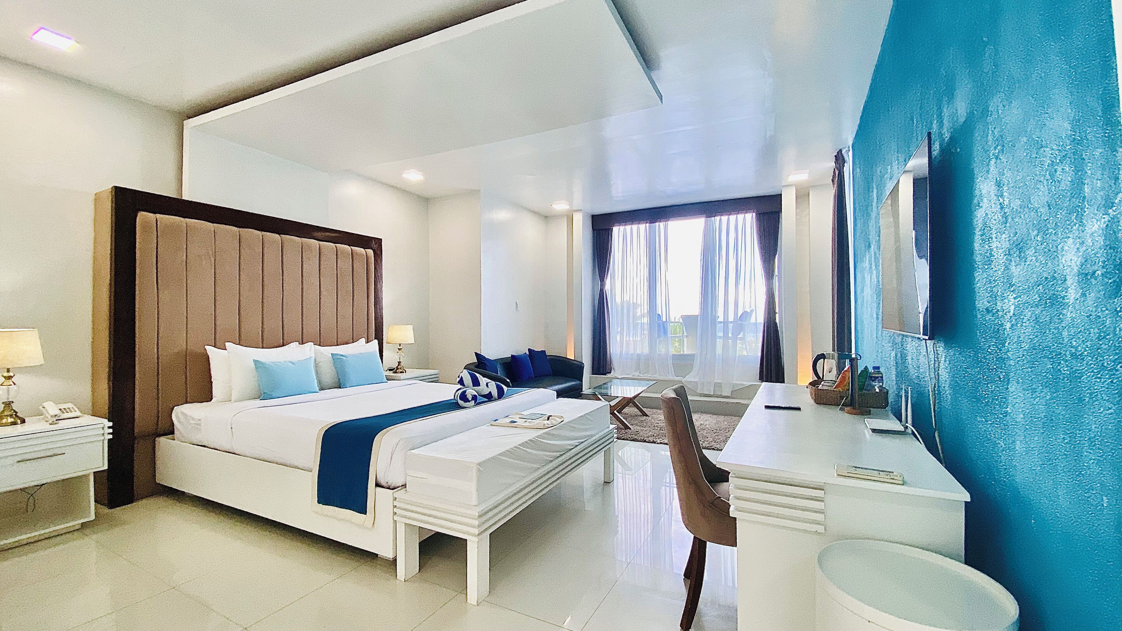 Une chambre d’hôtel moderne avec un grand lit, un bureau et une vue sur l’extérieur.