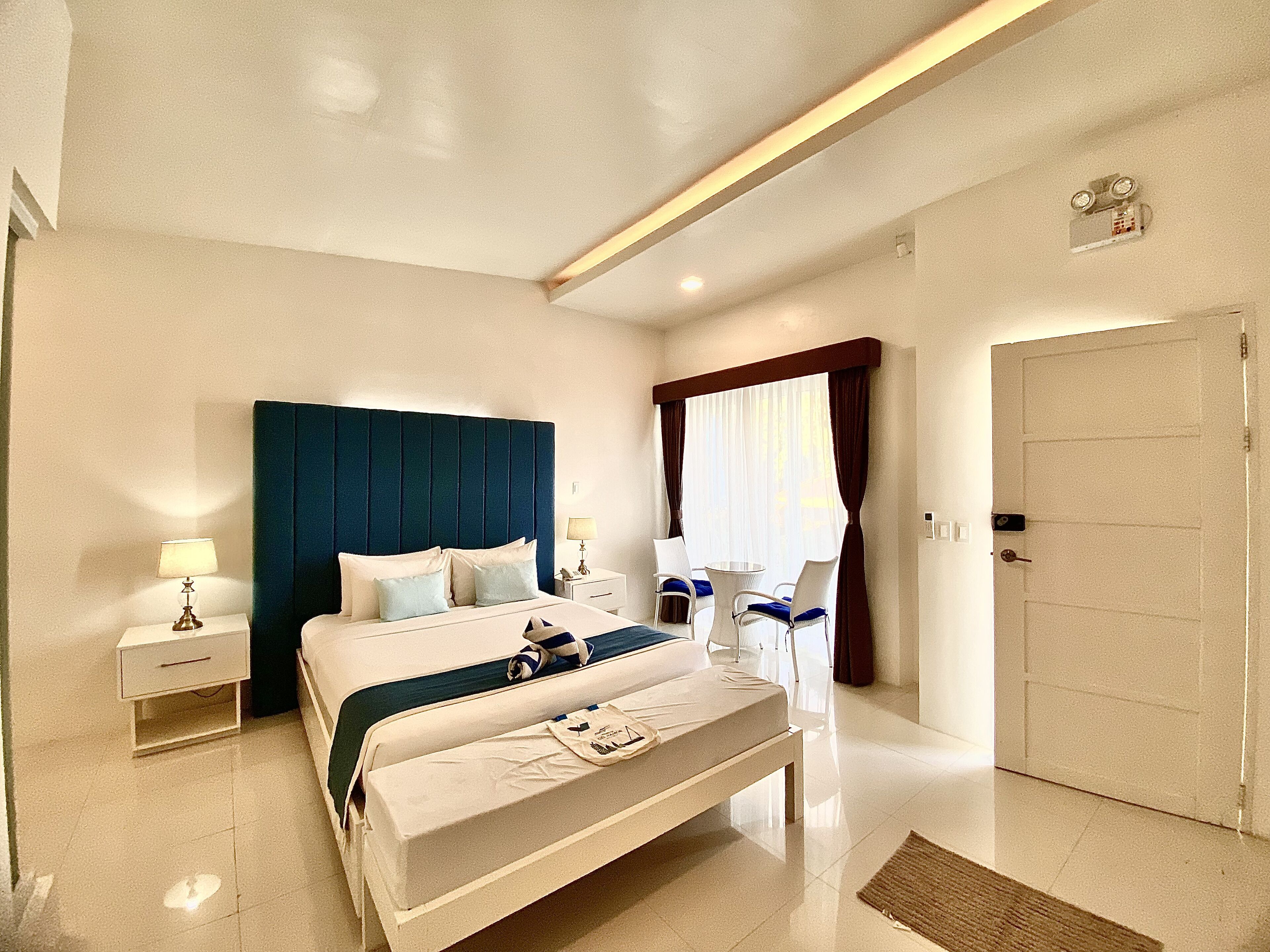A hotel room with a large bed, bedside tables, a desk, and a chair.