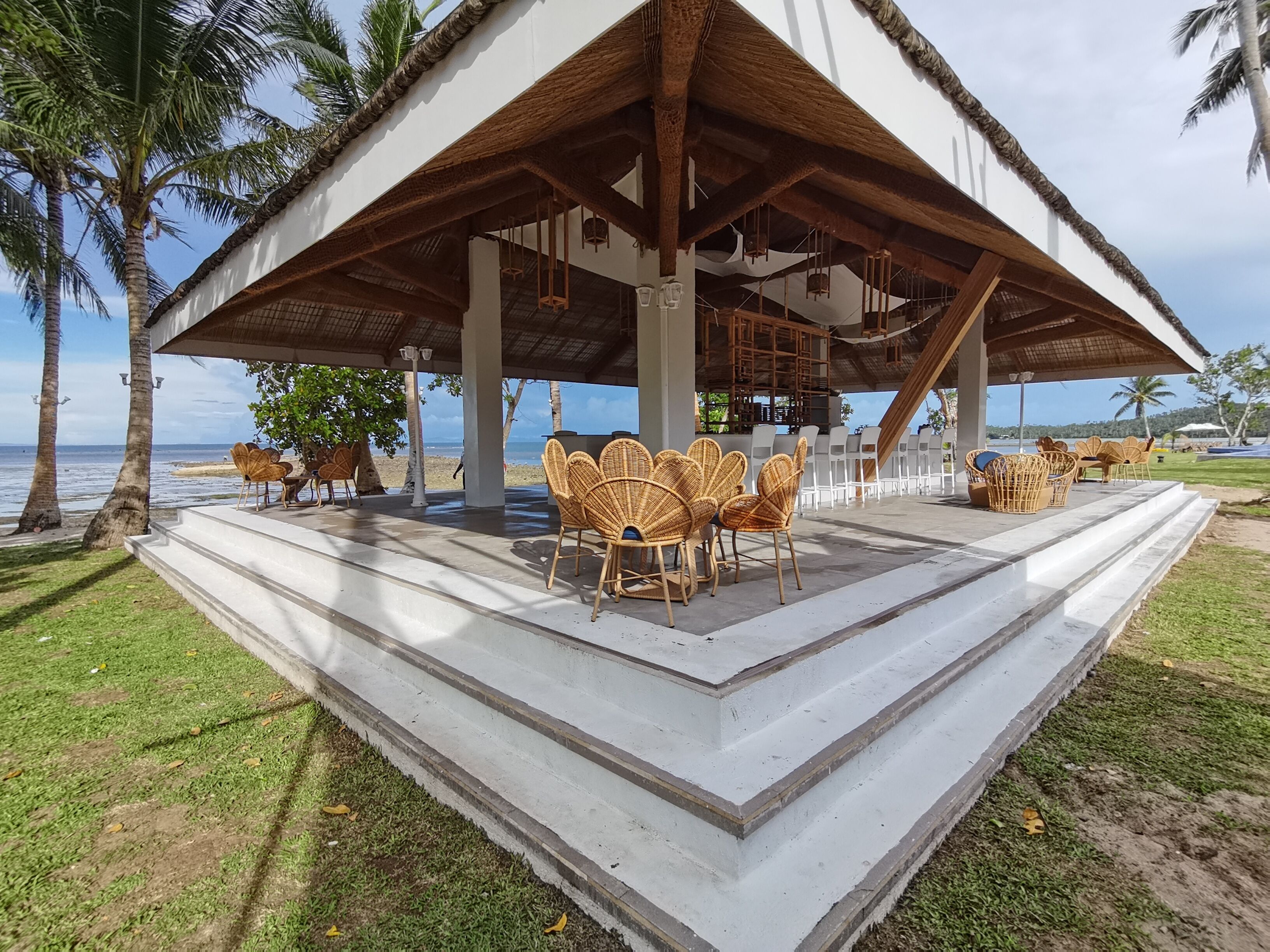 Un'area relax all'aperto con sedute e tavoli in vimini, con vista sulla spiaggia.