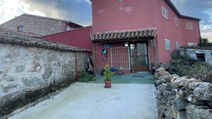 Un edificio rojo con techo de tejas, una pequeña ventana circular y una puerta con reja de metal.