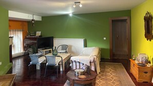 Una sala de estar con sofá, sillas, televisor y comedor.