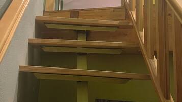 Eine Holztreppe mit Handlauf, die zu einem Raum mit gemusterten Vorhängen führt.