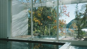 A modern indoor swimming pool with large windows offering views of autumn foliage and a distant mountain. - HOTEL and KOTEI SOKA (Kyotango)