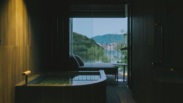 A modern bathroom with a glass-enclosed shower, a bathtub, and a seating area with a view of a mountainous landscape. - HOTEL and KOTEI SOKA (Kyotango)
