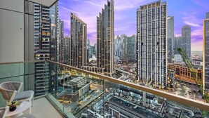 Un edificio de gran altura con un balcón de vidrio que domina un paisaje urbano.