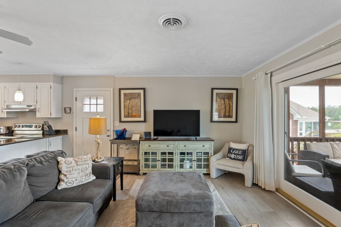A living room with a sofa, ottoman, TV, and a dining area with a table and chairs.