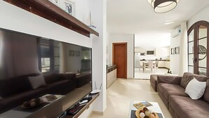 A modern living room with a large flat-screen TV, a coffee table with snacks, and a sofa. - Luxury Villa with Private Pool and Stunning Views in Playa Blanca, Lanzarote (Playa Blanca)