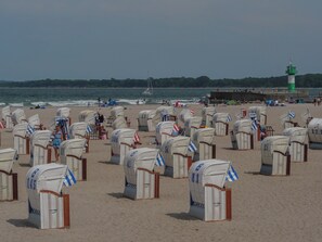 A beach with numerous wicker beach chairs arranged in rows.