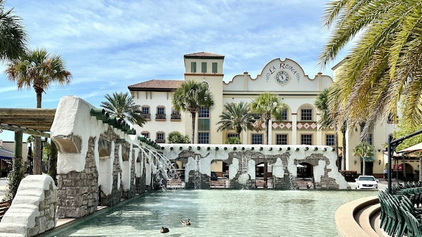 Edificio histórico con una fuente, piscina cristalina y zona de estar al aire libre.