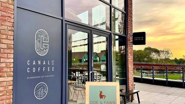 A modern coffee shop with large windows, a sign for 'Canal St Coffee', and a sign for 'Doe & Fawn Coffee Roasters' outside. - Experience comfort and convenience in this ideal short-term rental! (Milton Keynes)