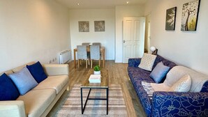 A living room with a sofa, a coffee table, and a dining area with chairs and a table. - Experience comfort and convenience in this ideal short-term rental! (Milton Keynes)