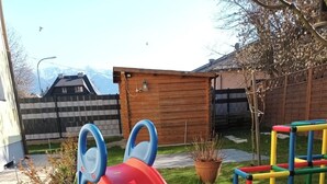 En lekplats med en rutschkana och en klätterställning i en trädgård.
