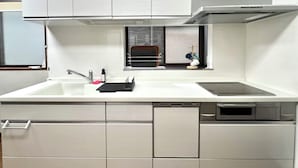 A modern kitchen with white cabinetry, a stainless steel sink, and a built-in dishwasher. - SUMITSUGU HOUSE Station (Kumamoto)