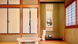 A traditional Japanese room with tatami flooring, a low wooden table, and shoji screens. - SUMITSUGU HOUSE Station (Kumamoto)