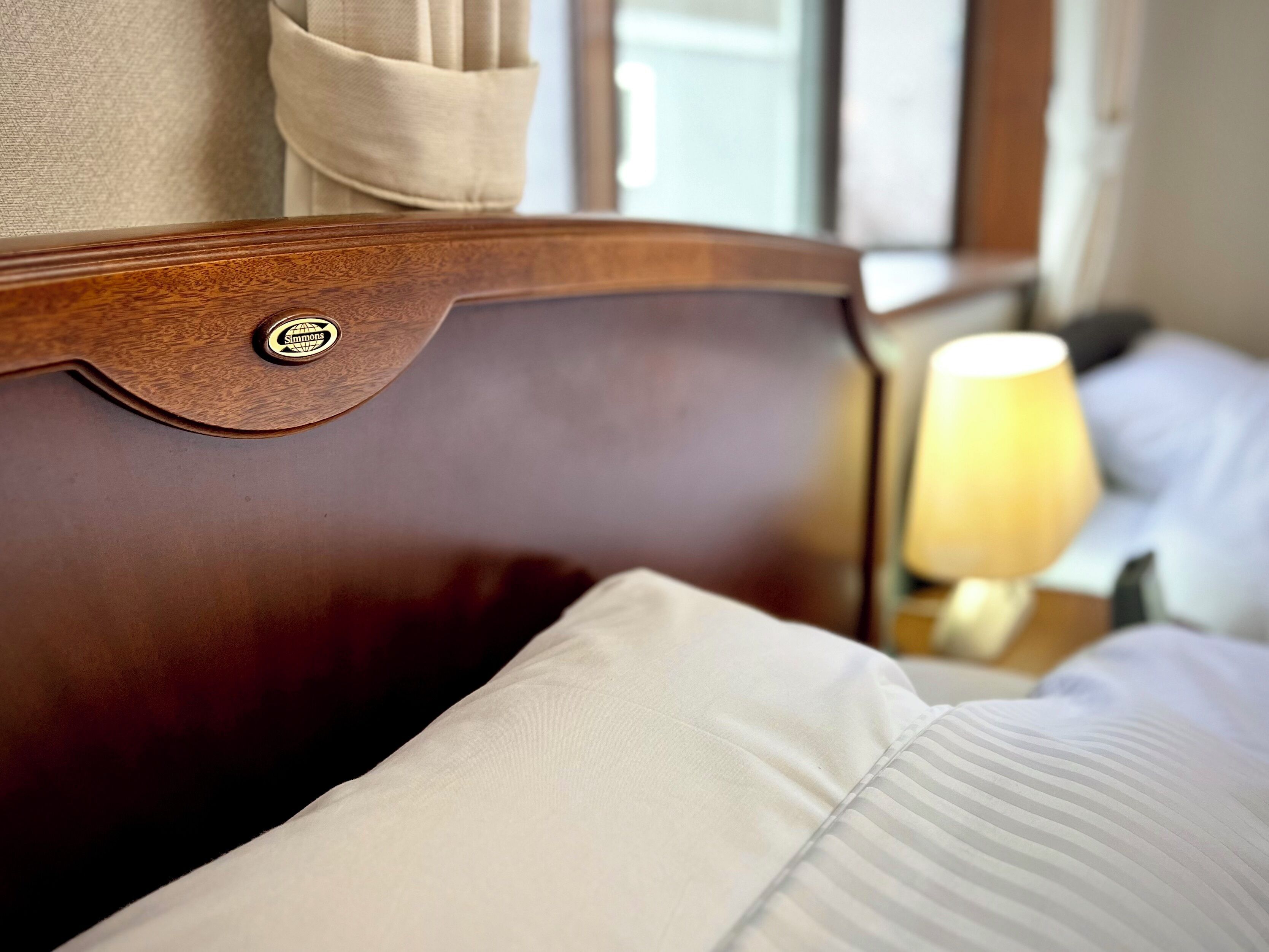 A wooden headboard with a pillow and a lamp on a bedside table.