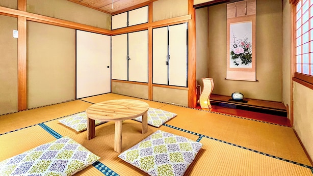 A traditional Japanese room with tatami flooring, a low wooden table, and sliding doors. - SUMITSUGU HOUSE Station (Kumamoto)