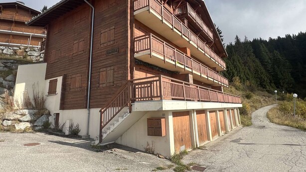 A multi-story wooden building with balconies, a staircase, and a gravel driveway. - 3-room apartment, near slopes, Les Saisies, sleeps 8 (Les Saisies)