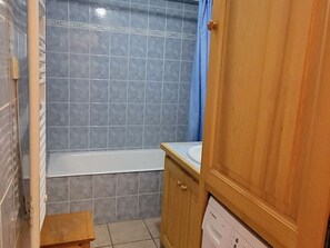 A bathroom with a bathtub, a wooden cabinet, and a small stool. - 3-room apartment, near slopes, Les Saisies, sleeps 8 (Les Saisies)