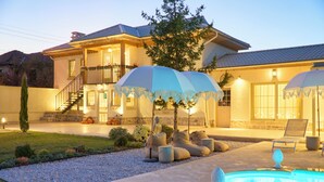 Una casa con piscina, area salotto esterna e patio ben illuminato.