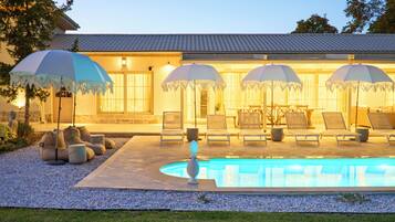 Relax by the pool surrounded by lounge chairs and umbrellas, with a decorative centerpiece nearby.