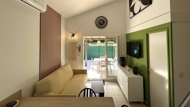 A compact living space with a sofa, dining table, and a TV mounted on the wall. - Renovated pavilion in Argelès-sur-Mer, air-conditioned and pool! (Argelès-sur-Mer)