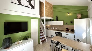 A modern kitchen with a dining area, green walls, and a flat-screen TV. - Renovated pavilion in Argelès-sur-Mer, air-conditioned and pool! (Argelès-sur-Mer)