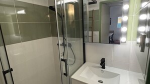 A bathroom with a glass shower enclosure, a white sink, and a mirror with lights. - Renovated pavilion in Argelès-sur-Mer, air-conditioned and pool! (Argelès-sur-Mer)
