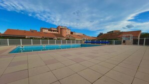 A swimming pool with a tiled deck, surrounded by buildings with red-tiled roofs. - Renovated pavilion in Argelès-sur-Mer, air-conditioned and pool! (Argelès-sur-Mer)