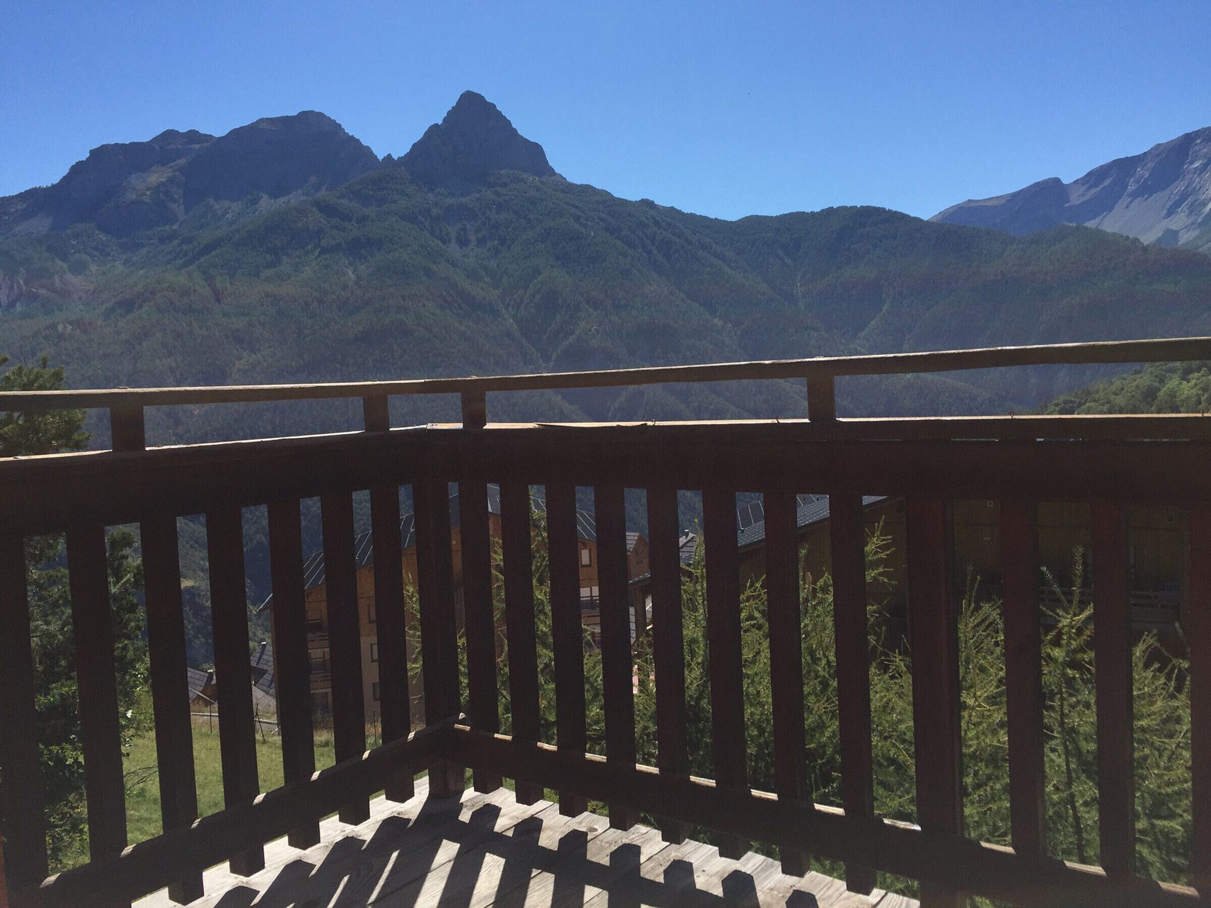 A wooden balcony with a view of a mountain range.