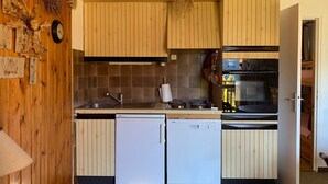 Une cuisine compacte avec des meubles en bois, un lave-vaisselle Bosch et un four encastré.