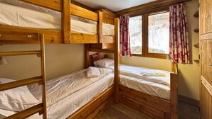 A compact, wooden cabin-style room with bunk beds, a window with curtains, and a ceiling light fixture. - Comfortable apt for 6 in Saint-Martin near slopes, parking, WiFi (Saint-Martin-de-Belleville)