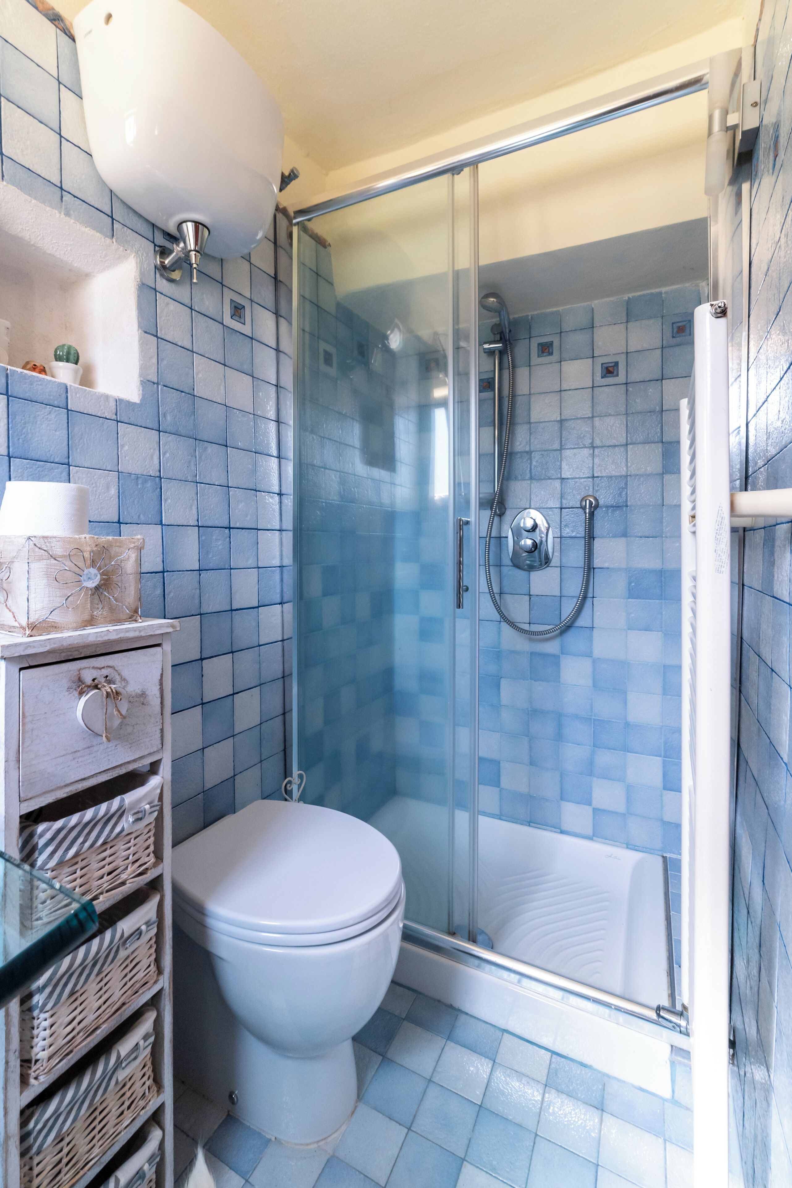 A bathroom with a glass-enclosed shower, a white toilet, and a tiled floor.